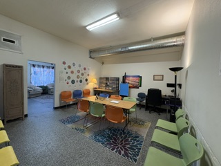 Break room with tables, colorful chairs, green sofas, and children's wall decorations in a community center