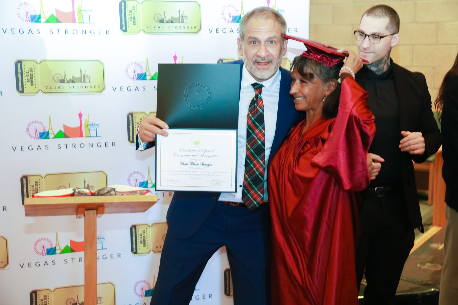 Man presents recovery graduation certificate to woman in red gown
