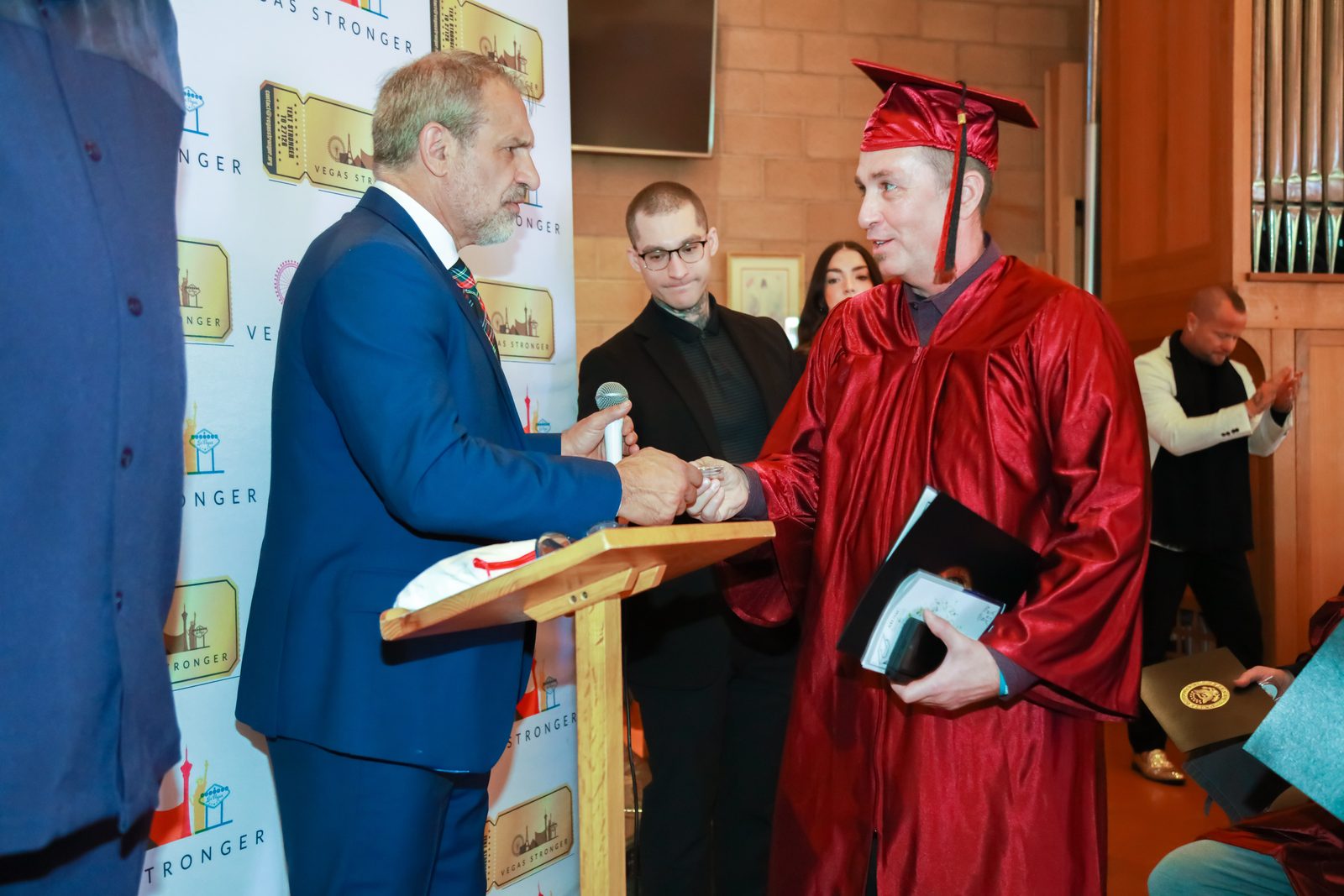 Presenter shakes hands with graduate holding diploma