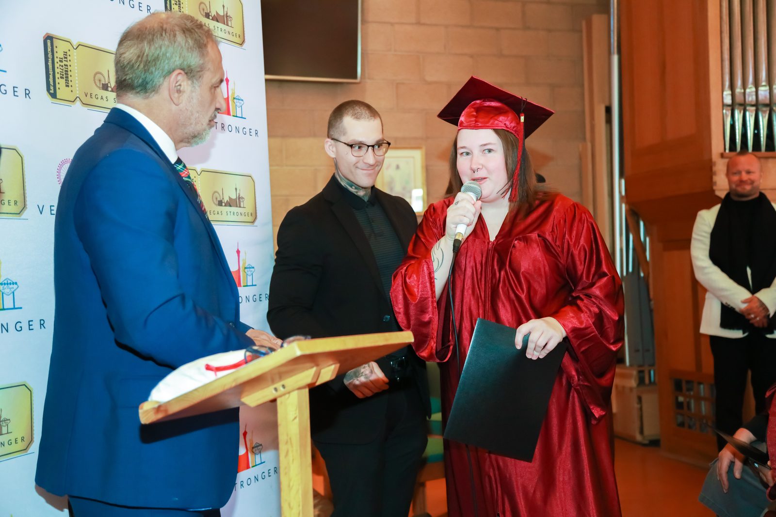 Graduate speaks holding diploma at Vegas Stronger podium
