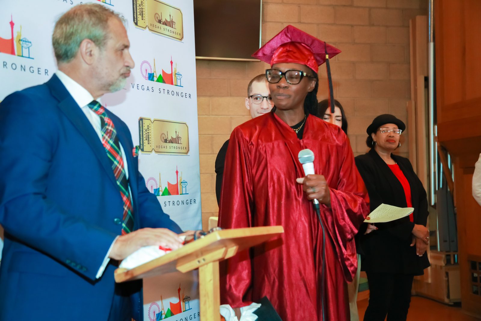 Smiling graduate stands with presenter at Vegas Stronger ceremony