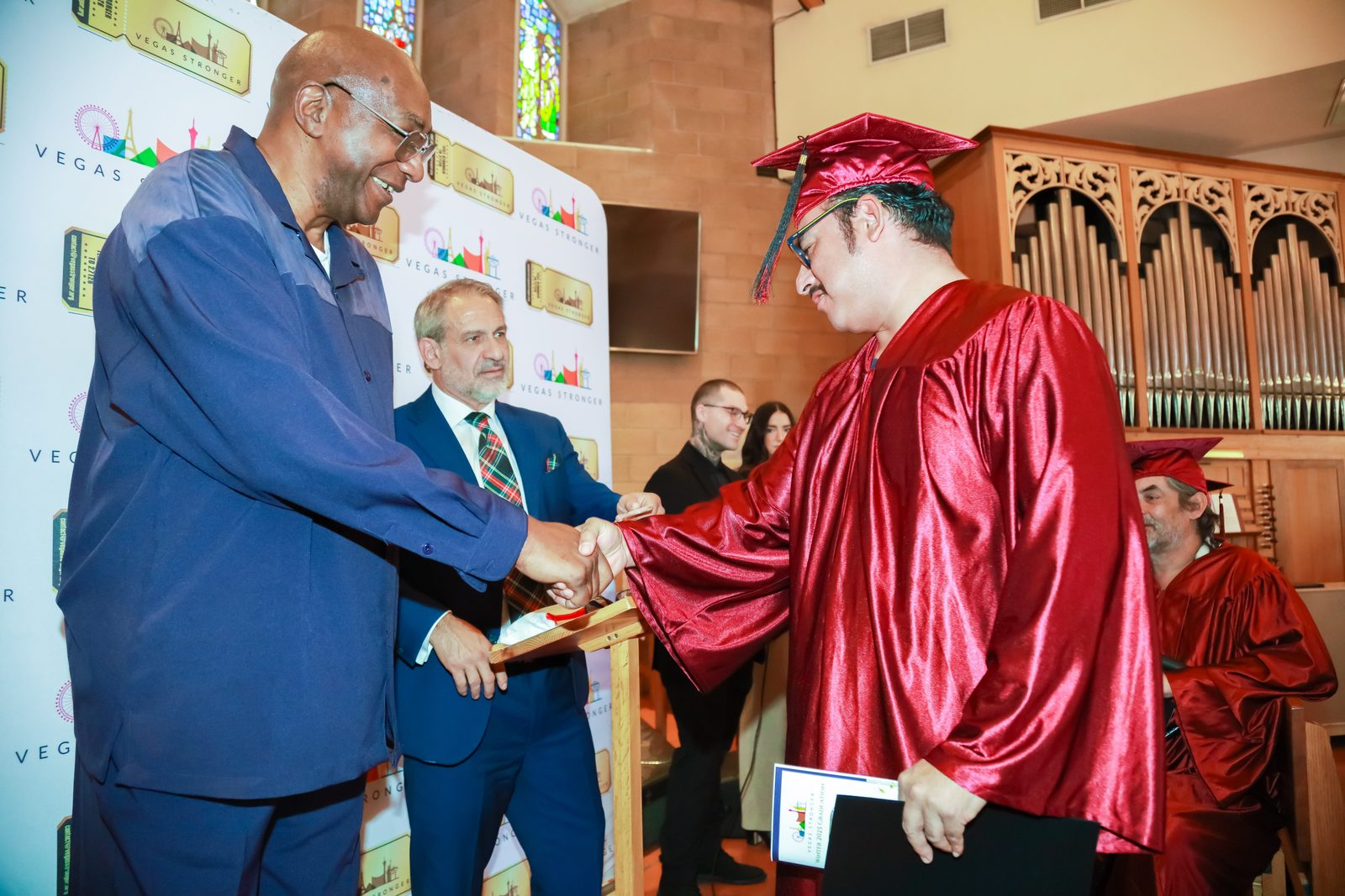 Man congratulates graduate holding diploma at ceremony