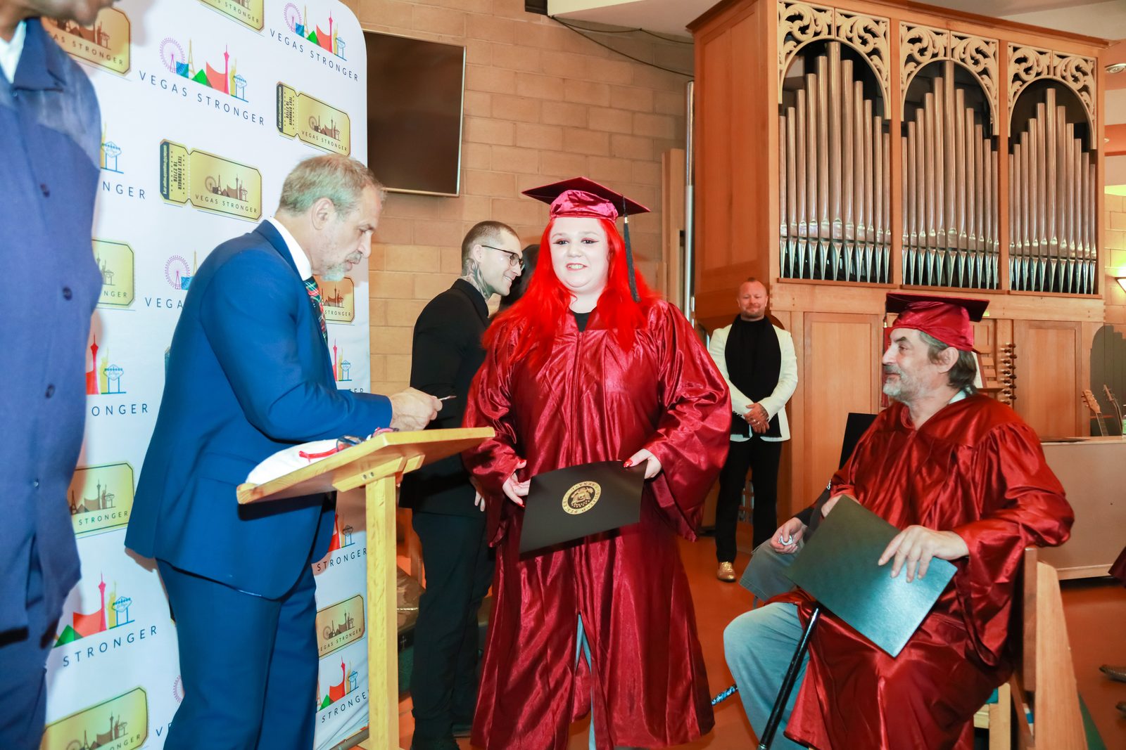 Graduate holds diploma at Vegas Stronger graduation podium