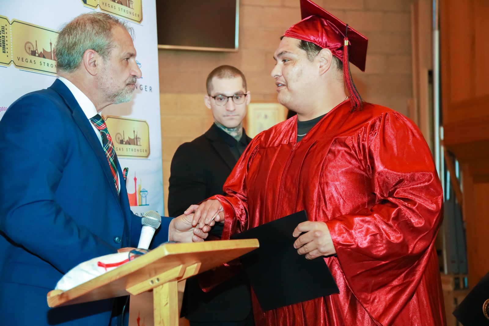 Presenter shakes hands with graduate holding diploma
