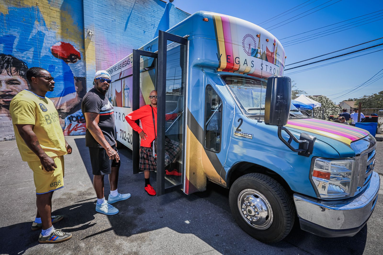 Three men beside Vegas Stronger community bus